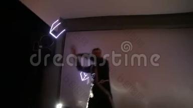 Led显示。一男一女在一个有背光的小舞台上，手中握着扭曲的LED风扇。